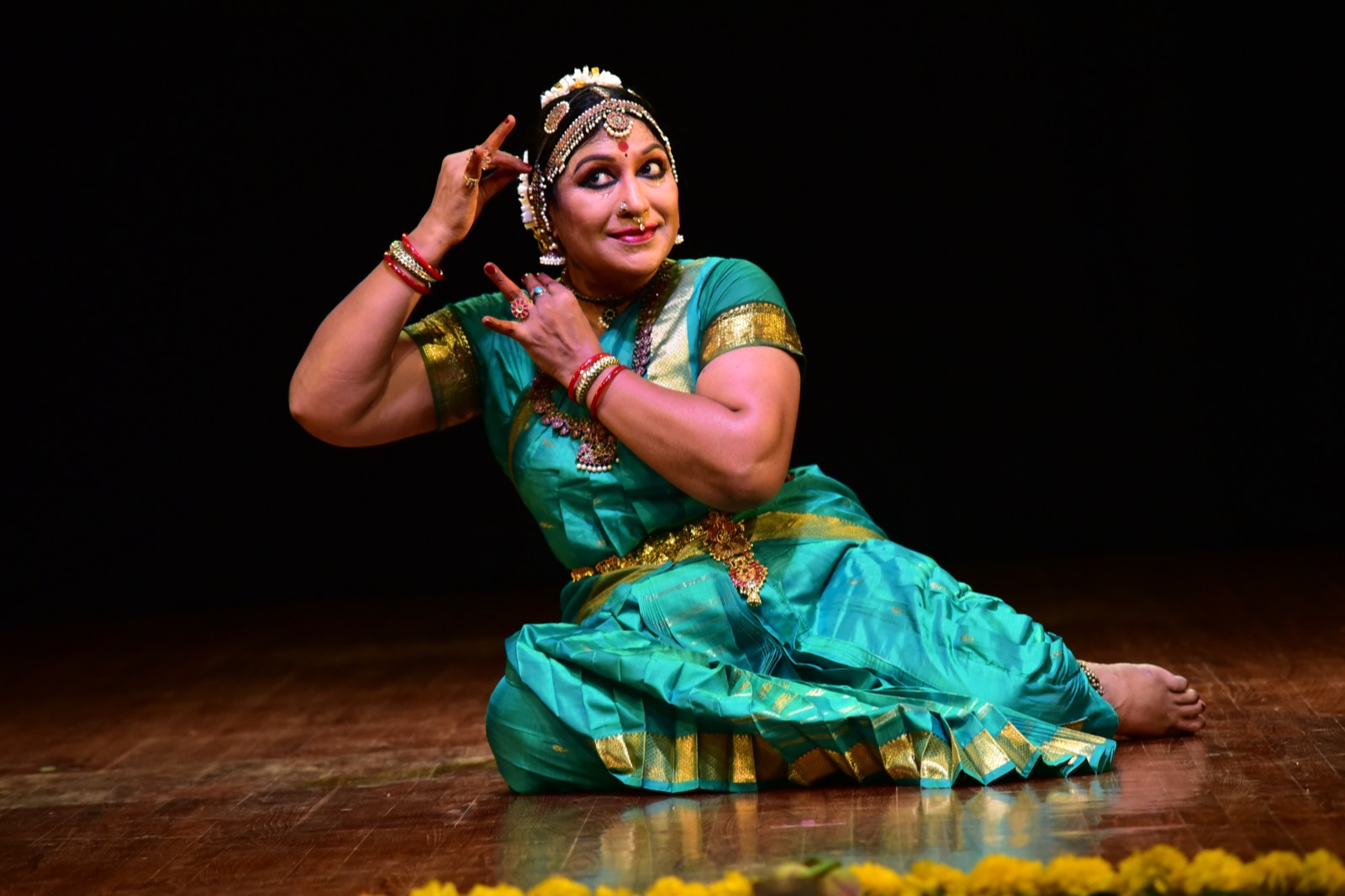 Seated performance in a turquoise and gold costume